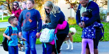 April and Rubin Doster, along with their 11-year-old daughter Mya, second from left, greet their other children, from left: Derek, 5, Savannah, 8 and Hailey, 7, after they get off of the school bus in their Palmyra neighborhood on Tuesday, Nov. 5, 2019.